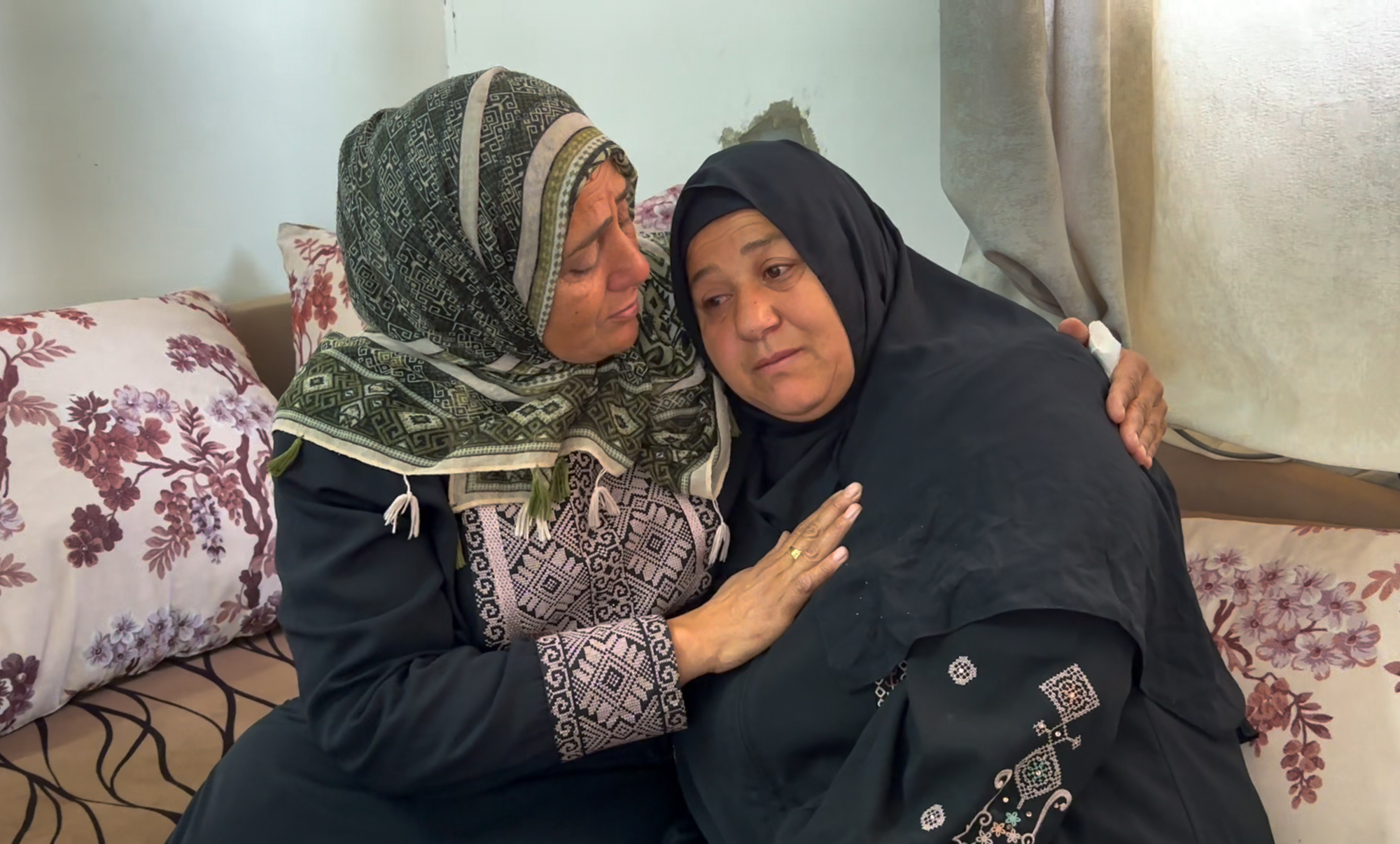 Amal leans on her sister's shoulder, too overwhelmed by her tears to speak